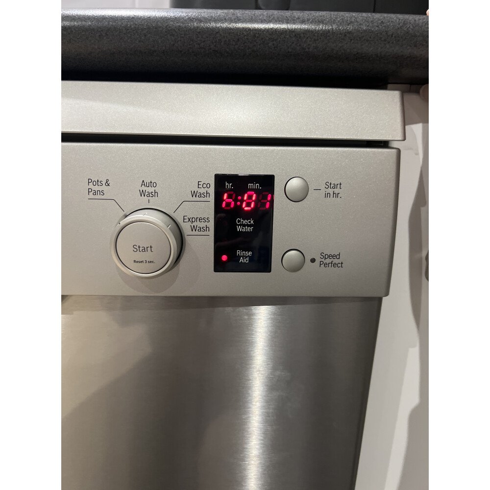 Close-up of a Bosch dishwasher on a modern kitchen floor with a blinking red InfoLight beam projected onto the tile, indicating a cycle interruption.