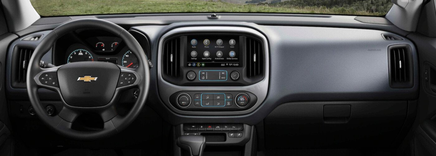 Chevrolet Silverado dashboard with a malfunctioning MyLink touch screen showing ghost touches and radio station flickering, DIY digitizer replacement tool on passenger seat.