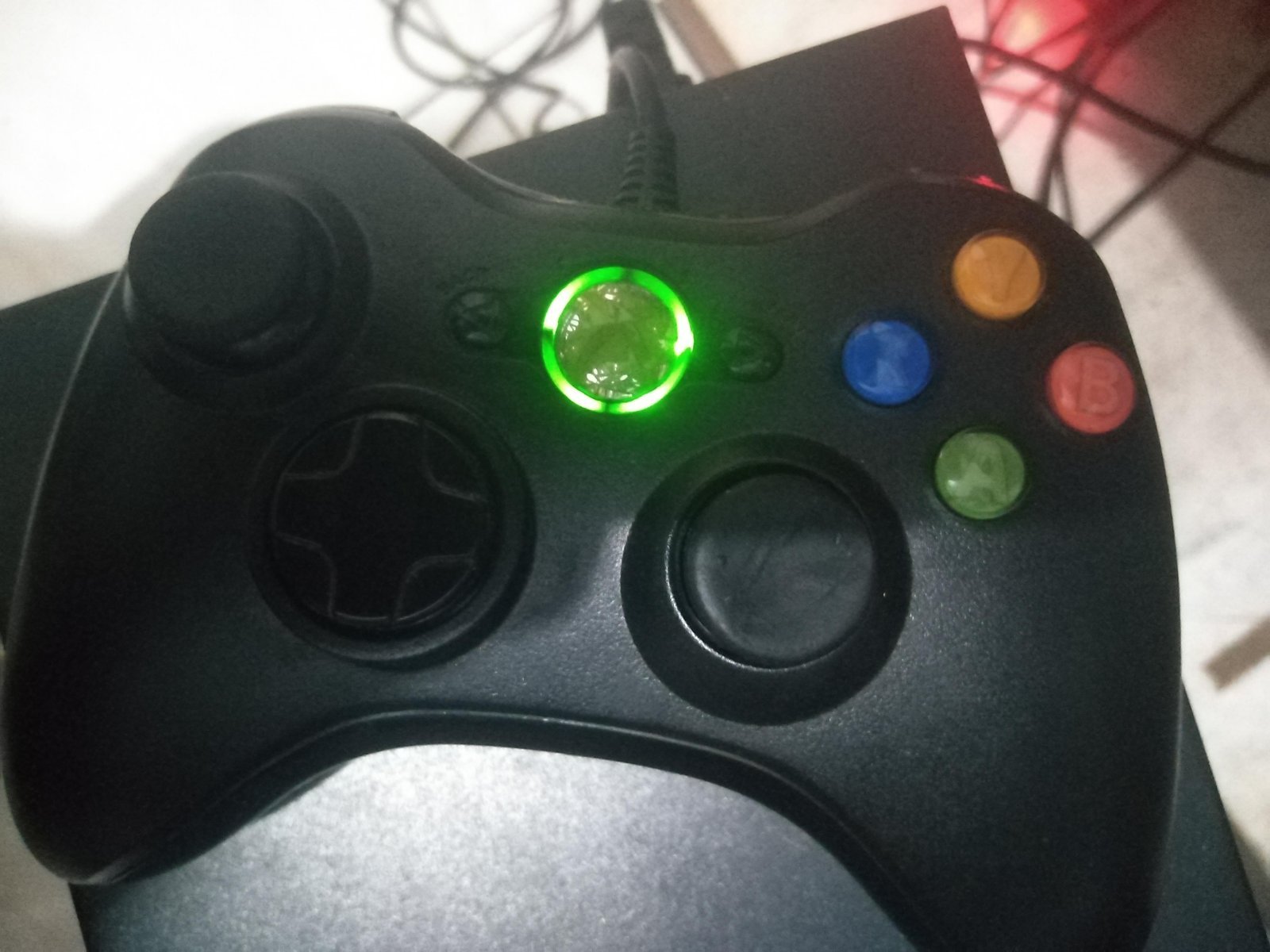 A finger pressing the sync button on a game console to initiate pairing.