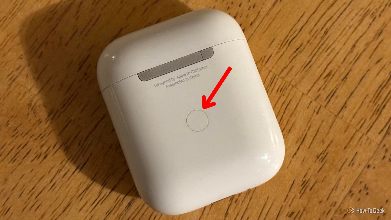 Hands holding a wireless charging case while checking the device status light.