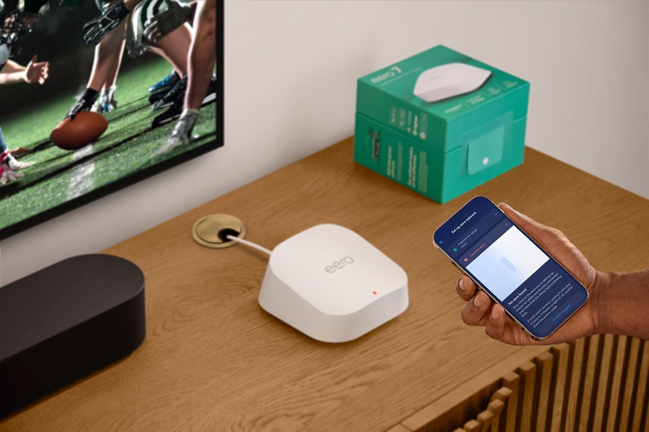 A smartphone app interface next to an eero router during setup mode.