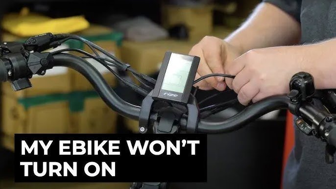 A rider pressing the power button on an electric bike display to reset.