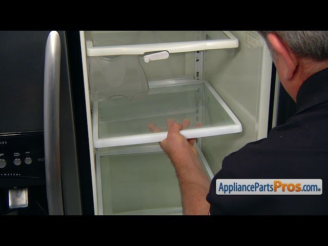 Hands carefully checking a loose light bulb connection inside a refrigerator socket.