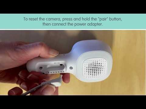A modern baby monitor camera displaying a static green light in a nursery.