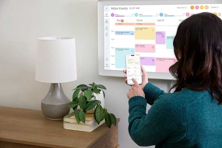 A home Wi-Fi router sits on a table near a digital calendar screen.